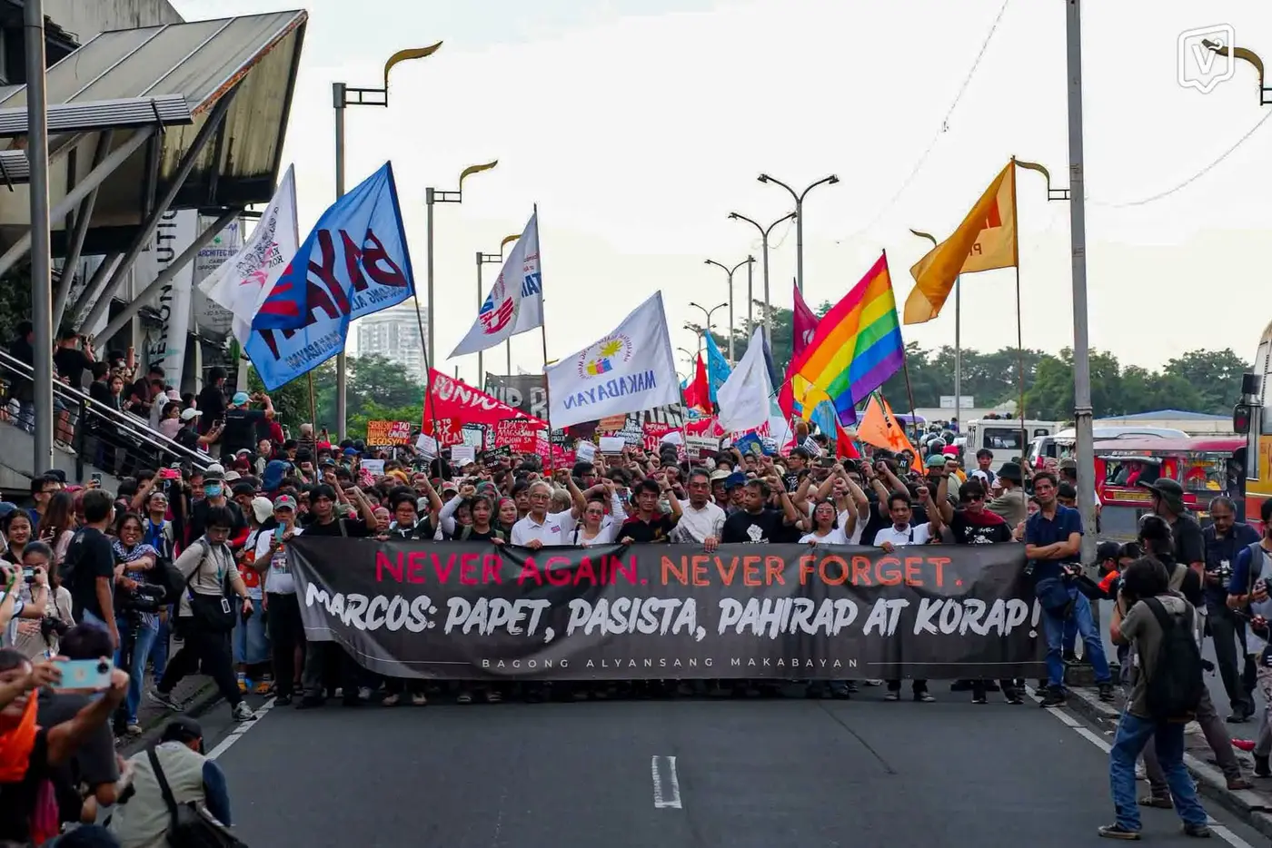 Marchers holding a wide black banner reading Never Again, Never Forget, Marcos papet pasista pahirap at korap